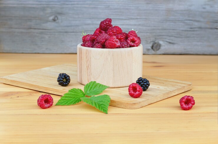 Raspberries and hedgehogs on a light wooden table.