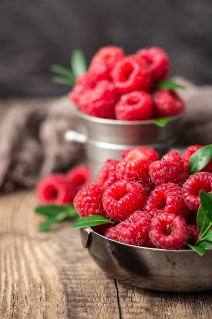 Raspberries in metal dishes on wooden table