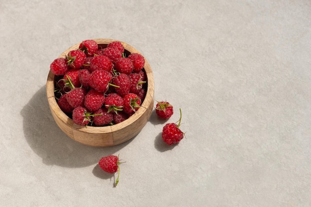 Photo raspberries in a wooden cup on a gray background macro