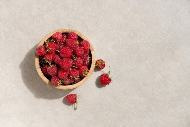 Raspberries in a wooden cup on a gray background Macro