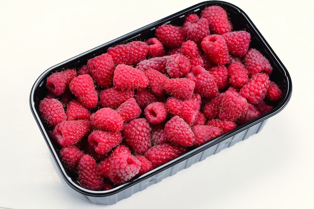 Raspberry in black container isolated on white.