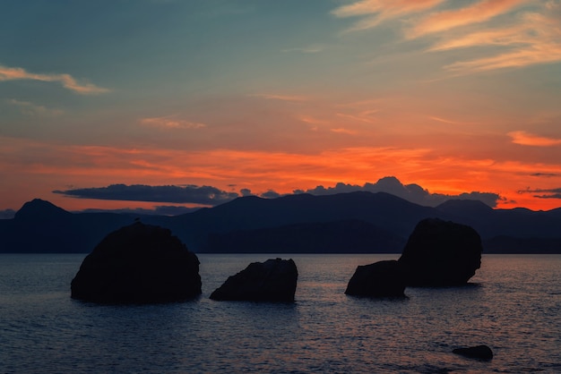 Raspberry blue sunset on the sea coast, calm, large stones in the foreground