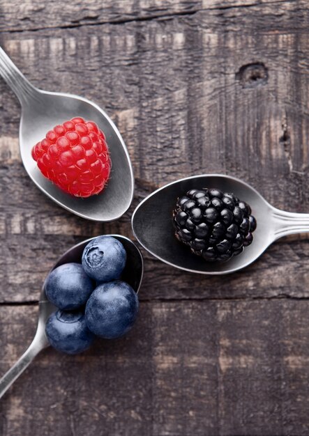 Raspberry, blueberries and blackberry on spoons