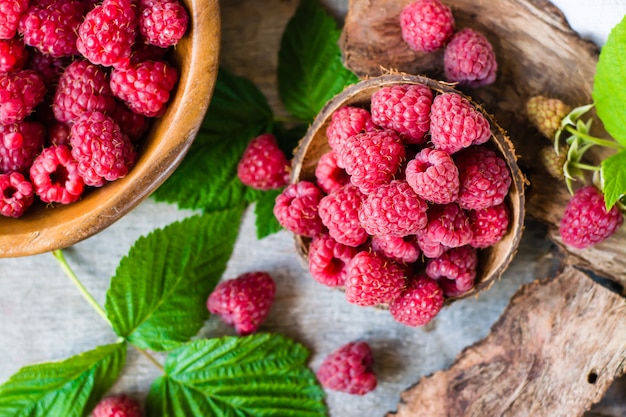 Raspberry in a bowl and in a plate, berries and leaves on a shabby wood. 