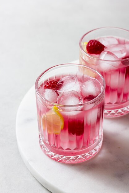 Photo raspberry cocktail with ice in a glass on a light background