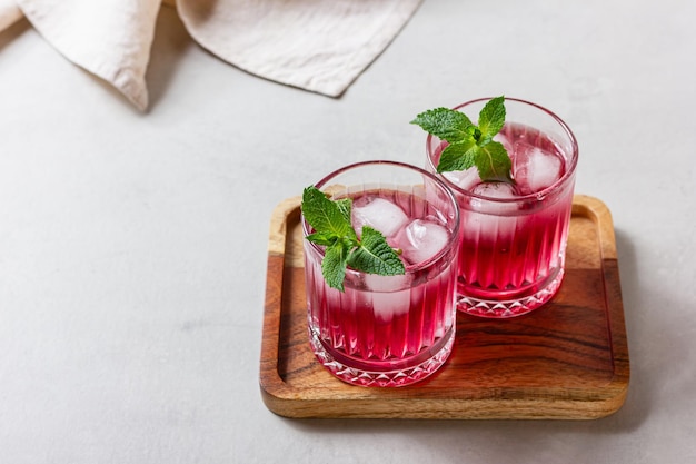 Foto cocktail di lamponi con ghiaccio in un bicchiere su uno sfondo chiaro