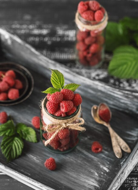 Raspberry in a glass jar on dark wooden table.. Healthy food concept. Fresh organic berries