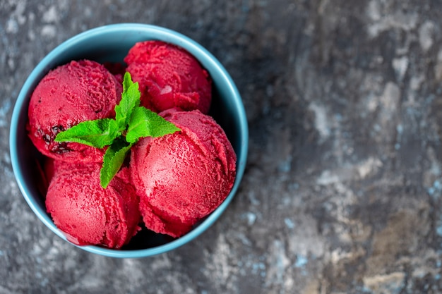 Raspberry ice cream in bowl on stone table