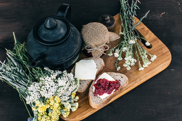 Marmellata di lamponi e pane con burro in un barattolo e tisana calda sul tavolo di legno pranzo colazione