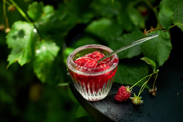 Raspberry jam in glass bowl on a black background