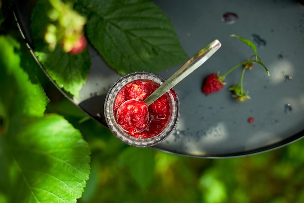 Raspberry jam in glass bowl on a black background