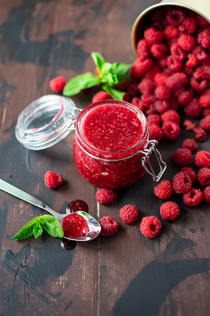 raspberry jam in a glass jar on a wooden table, homemade jam