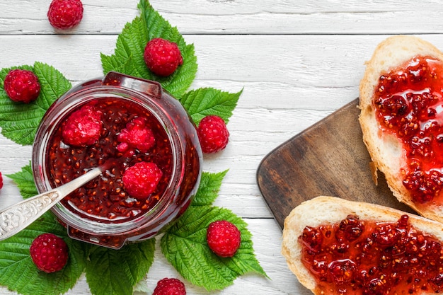 Raspberry jam and sandwiches with fresh raspberry on white wooden table