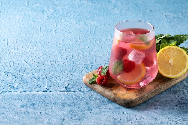 Raspberry lemonade drink in glass on blue backgroundxa