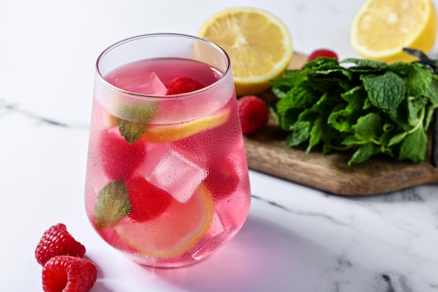 Raspberry lemonade drink in glass on white marble