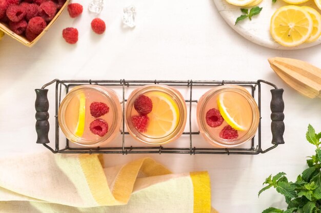 Raspberry lemonade in drinking mason jars on a white table.