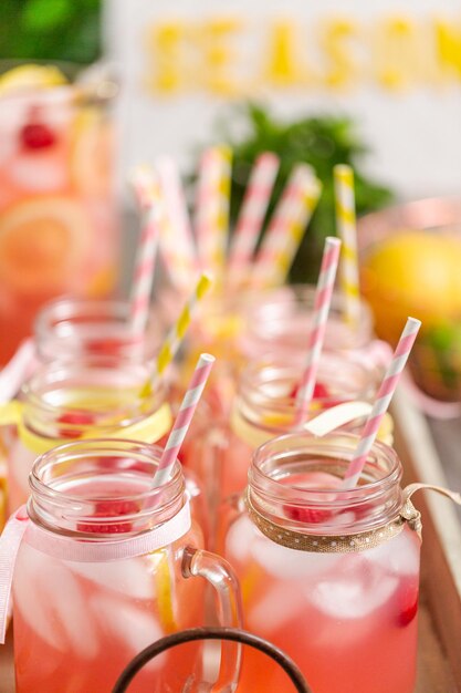 Photo raspberry lemonade garnished with fresh lemon and raspberries in drinking mason jars.