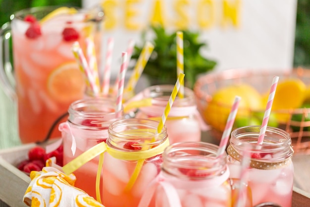 Raspberry lemonade garnished with fresh lemon and raspberries in drinking mason jars.