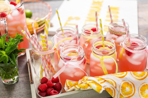 Photo raspberry lemonade garnished with fresh lemon and raspberries in drinking mason jars.