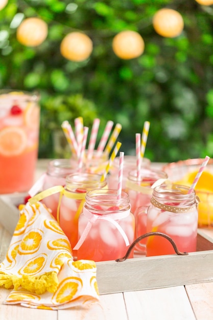 Raspberry lemonade garnished with fresh lemon and raspberries in drinking mason jars.