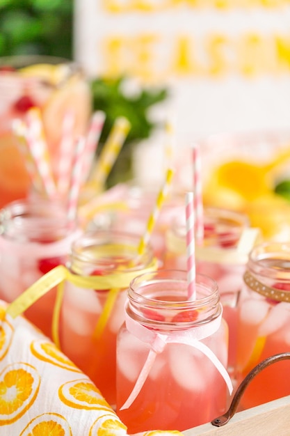 Raspberry lemonade garnished with fresh lemon and raspberries in drinking mason jars.