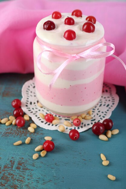 Raspberry milk dessert in glass jar on color wooden background