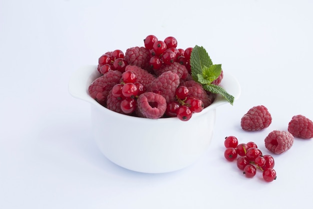 Raspberry and red currant in the white bowl on the white