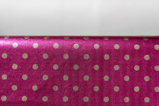 Raspberry shiny wrapping paper with polka dots with a fold, Foil for the design of gift wrapping, wallpaper, Stylish shiny texture