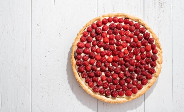 Raspberry tart on white wooden background top view