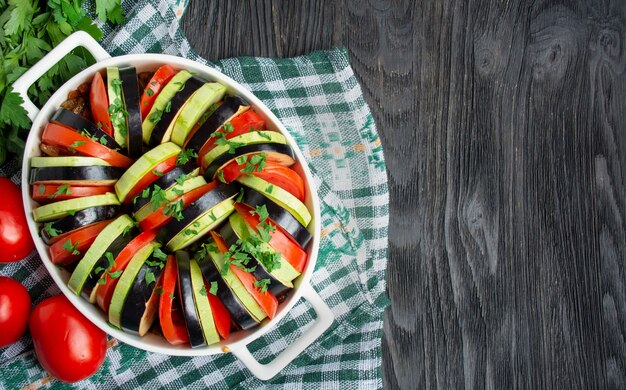 Ratatouille op een donkere houten ondergrond. Traditionele Franse groenteschotel. Gebakken groenten in de oven. Eten koken. Vegetarisch eten. Ruimte kopiëren.