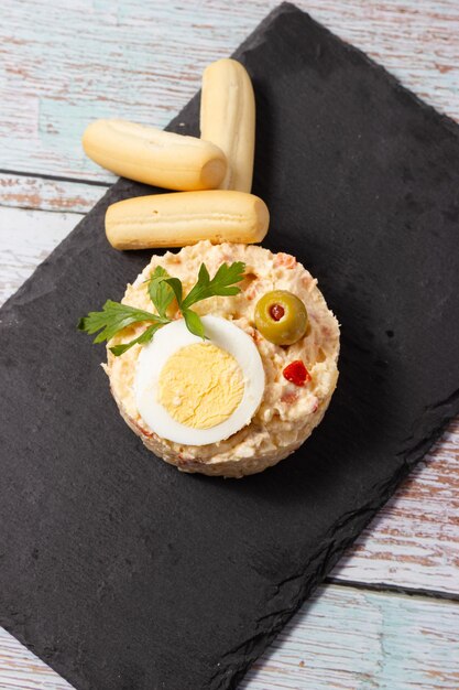 Photo ration of russian salad on black slate plate