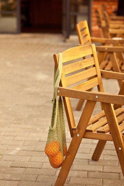 오렌지 과일이 든 그물 가방이 있는 등나무 카페 의자. 거리 카페.