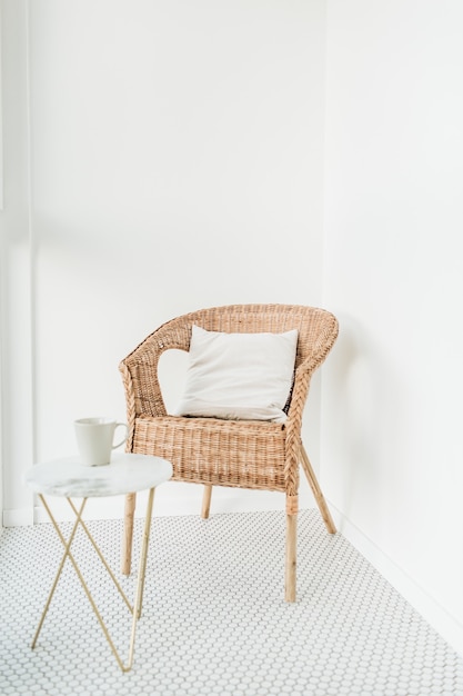 モザイクの床が付いているバルコニーの枕および大理石のコーヒーテーブルが付いている籐の椅子