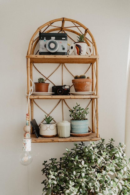 Photo rattan shelf with plants, vintage camera, ebook and a matcha latte. rustic aesthetic home style.