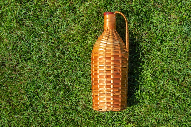 Rattan wine bottle laying on green grass lawn , pic nic concept