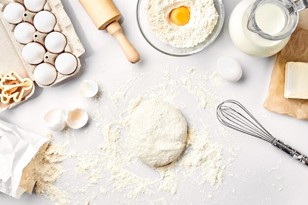 Rauw deeg klaar om te kneden op witte tafel Bakkerij ingrediënten eieren meel boter Vormen voor het maken van koekjes