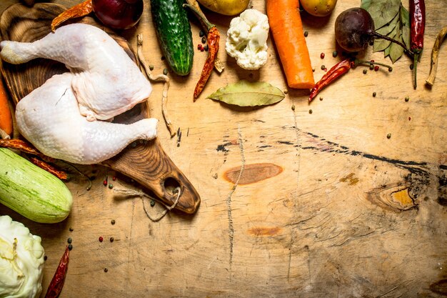 Rauw kippenbeen met groenten voor het koken van soep. Op een houten tafel.