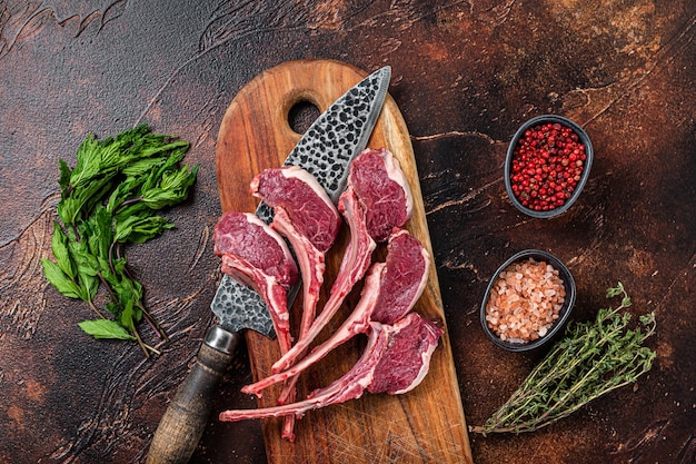 Rauw lamsvlees, schaapskoteletten steaks op een houten bord. Donkere achtergrond. Bovenaanzicht.