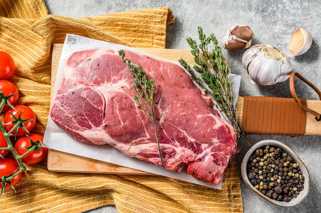 Rauw marmer varkensvlees steak op een houten snijplank. Biologisch vlees. Grijze achtergrond. Bovenaanzicht.