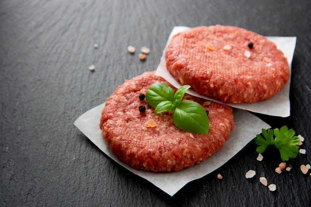 Rauw rood vlees cotlets, hamburgers koken. Gehakt rood vlees op zwarte achtergrond