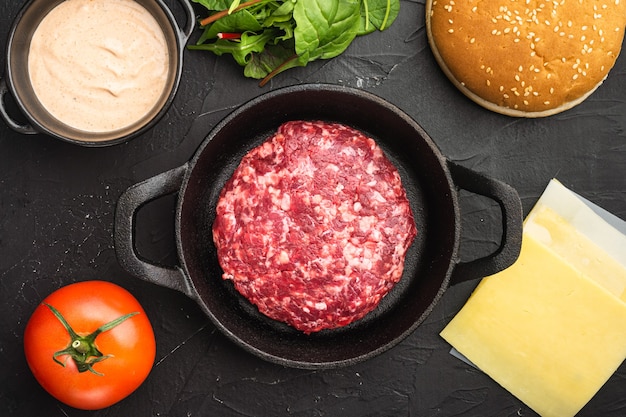 Rauw Rundergehakt Hamburger steak schnitzels set, op zwarte stenen tafel, bovenaanzicht plat lag