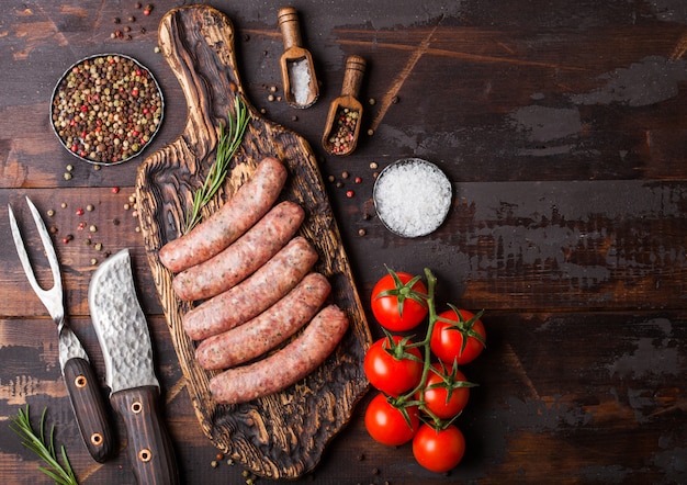 Rauw rundvlees en varkensvlees worst op oude snijplank met vintage mes en vork