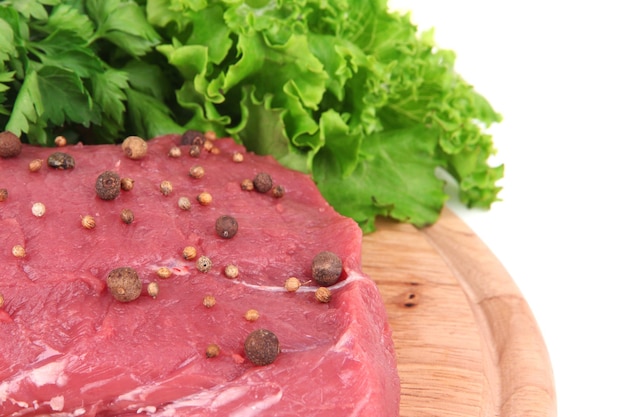 Foto rauw rundvlees met specerijen en groenten op een houten snijplank van dichtbij