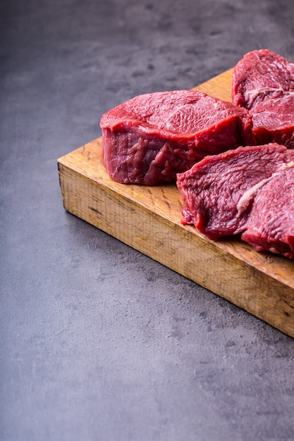 Rauw rundvlees steaks op een houten bord.