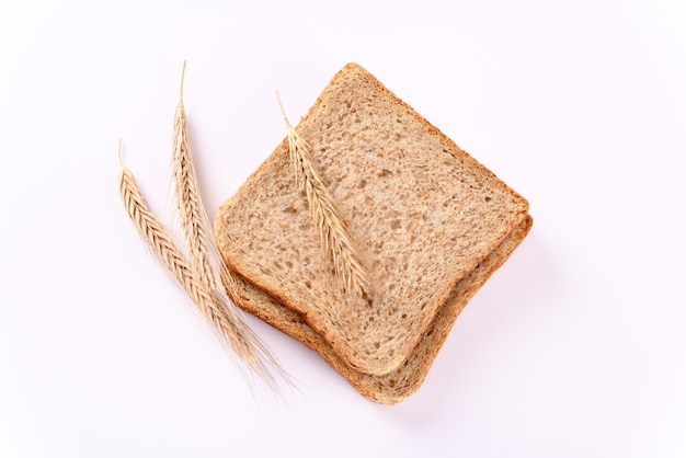 Rauw toastbrood met tarweoren en een fles olie op witte achtergrond