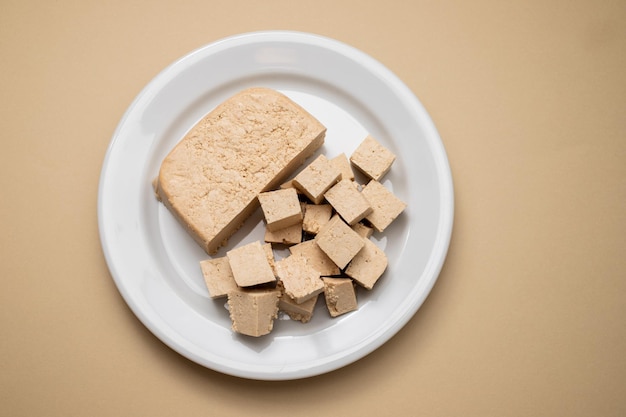 Rauw tofu blok op wit schaaltje op bruin