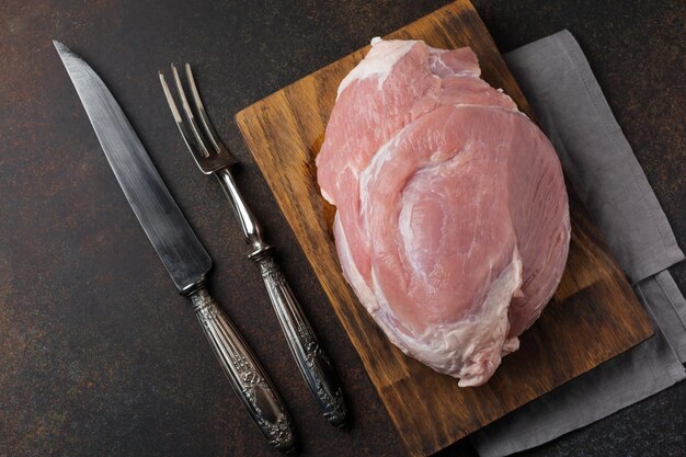 Rauw varkensvlees op een houten snijplank op een leisteen, steen of beton.
