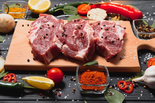 Rauw varkensvlees op houten snijplank aan de keukentafel voor het koken van varkensvlees steak geroosterd of gegrild met ingrediënten kruiden en specerijen