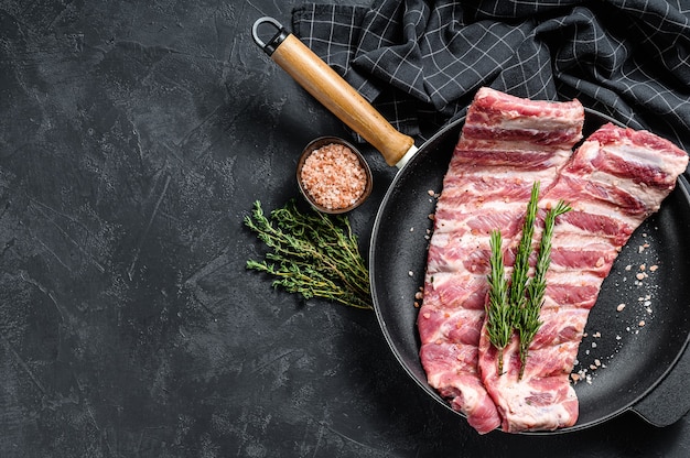 Rauw varkensvlees spareribs met kruiden en specerijen in een pan