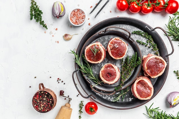 Rauw vers gemarmerd vlees Steak filet mignon. Ossenhaas steaks omwikkeld met spek geserveerd op oud vlees dienblad op een lichte achtergrond. bovenaanzicht.